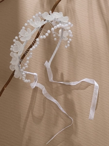 Détails d'un serre-tête de mariée fait main avec fleurs en acrylique, perles et rubans