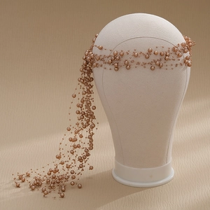Close-up of champagne gold pearl bridal headband with tassel detail on a mannequin