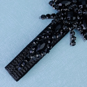 Vue détaillée de cristaux noirs cousus main et paillettes sur un bandeau en tulle fin
