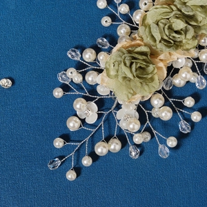 Detail of bridal hair accessory with green fabric roses, white pearls, and crystals