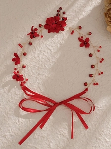 Détail de fleurs en tissu rouge et perles de cristal sur un bandeau de mariée avec rubans