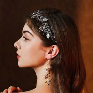 Detailed shot of handmade bridal hair vine and earrings with crystal beads and metal leaves