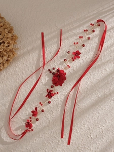 Détail de fleurs en soie rouge avec perles et cristaux sur un bandeau de mariée