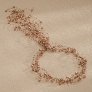 Close-up of woven rose gold wire headband with elegant pearls for bridal hair styling