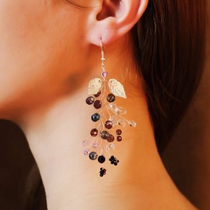 Detailed close-up of handmade gold bridal earrings with crystal beads and metal leaves