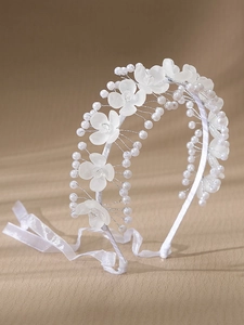 Détail d'un serre-tête de mariée avec fleurs en acrylique givré, perles et ruban blanc