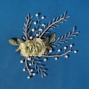 Macro detail of handmade bridal hair clip with green flowers, pearls and crystal beads