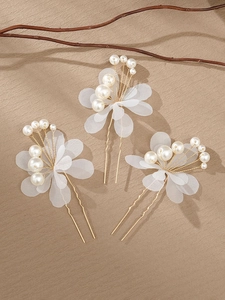 Detail of three-piece bridal hair pins with white mesh flowers and pearls on golden U-pins