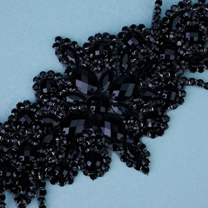 Détails de cristaux noirs facettés et strass brillants sur une base en tulle noir