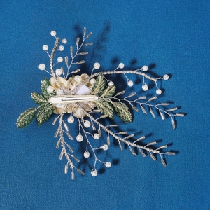 Detail of bridal hair clip with green fabric leaves, white pearls and crystal beads