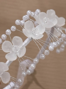 Détail macro du serre-tête de mariée avec fleurs en acrylique et perles blanches