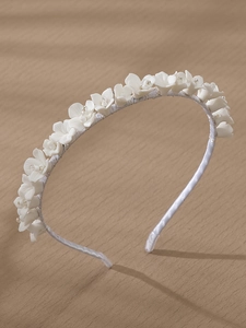 Detail of white ceramic flowers and transparent beads on a silk-wrapped bridal headband