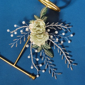 Detail of green floral bridal hairpiece with pearls and crystals on blue background