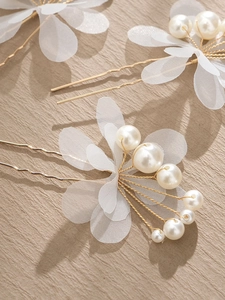 Detail of bridal hair pins with mesh flower petals and cream pearls on gold pins