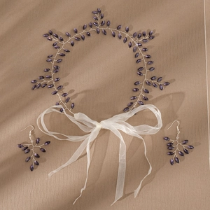 Detail view of silver bridal hair vine and earrings set with purple marquise crystals