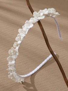 Close-up of elegant bridal headband featuring white ceramic flowers and bead details