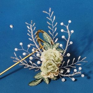 Detailed close-up of handmade bridal hairclip with green flowers, pearls and crystals