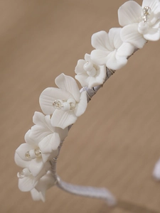 Close-up of white ceramic flowers and silver wire weaving on a bridal headband