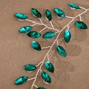 Macro shot of emerald green stones and silver wire branches on bridal headband