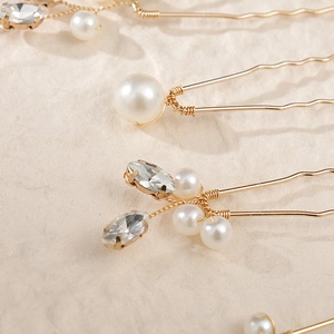 Detail of handcrafted gold hair pins with elegant white pearls and marquise rhinestones