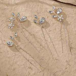 Detail of four handmade silver bridal hair pins with crystals and pearls on beige texture
