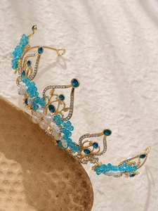 Detailed close-up of Baroque crown with blue crystals and pearls on golden base
