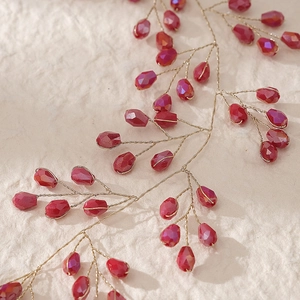 Détail d'un serre-tête de mariée fait main avec perles de cristal rouges et fil doré