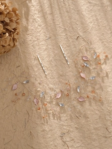 Detailed macro view of handmade crystal bridal headpiece with pink enamel leaves and rhinestones