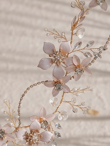 Détail d'un bandeau de mariée artisanal avec fleurs en métal, perles et cristaux