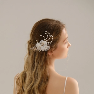 Detailed close-up of white silk flower hair clip with pearls and golden leaves on model