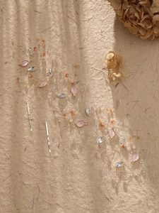 Detail of handmade crystal hair vine with pink leaves and beads on textured paper