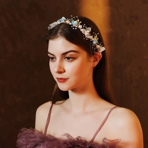 Nahaufnahme von handgefertigtem Goldblatt und blauem Blumen-Brauthaarband am Modell