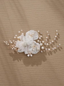 Detail of handmade bridal hair clip with white mesh flowers and golden pearl accents