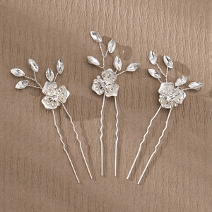 Macro detail of three silver bridal hair pins with crystals on a wooden surface