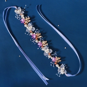 Detail eines handgefertigten Brautstirnbands mit Goldblättern, Harzblüten und Perlen auf Blau