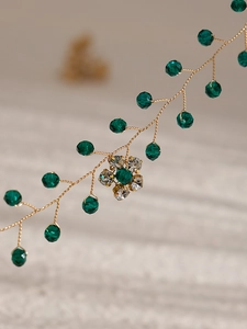 Dettaglio macro di tralcio per capelli sposa con cristalli verde smeraldo e filo d'oro