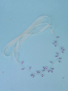Close-up of handmade purple crystal bridal hair vine with silver wire and white ribbon