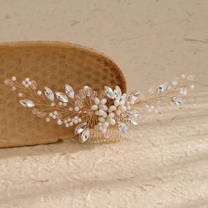 Elegant bridal hair comb with pearls and clear crystals on a warm natural stone backdrop