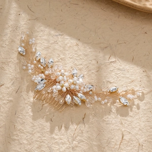 Close-up of handmade bridal hair comb with gold leaves, white pearls and crystals