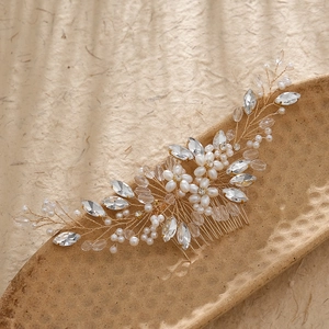 Elegant gold bridal hair comb with pearls and rhinestones on a rustic ceramic plate