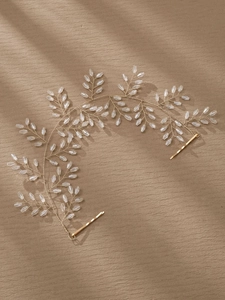 Detail von handgefertigtem Brauthaarschmuck mit Kristallperlen und Golddraht auf Braun