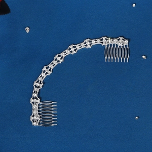 Detailed view of silver rhinestone bridal hair comb with marquise crystals on blue fabric
