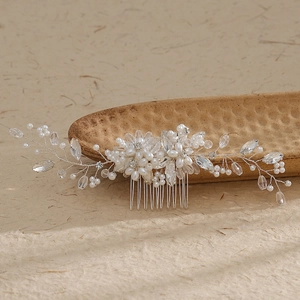 Detail of bridal hair comb with pearls and crystals on a rustic textured tray