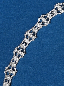 Close-up of a silver bridal hair comb with geometric rhinestones on dark blue backdrop