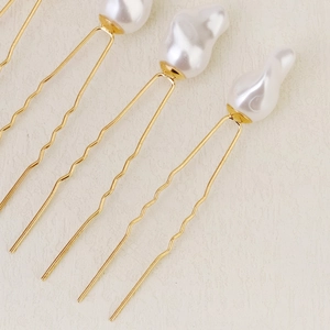 Détail d'épingles à cheveux dorées en U avec perles blanches baroques et tiges ondulées