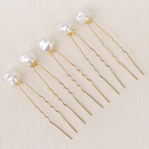 Vue macro détaillée de six épingles à cheveux dorées avec perles en ligne parallèle