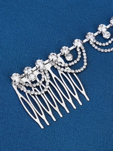 Detailed close-up of a silver bridal hair comb with rhinestones and fringe chains
