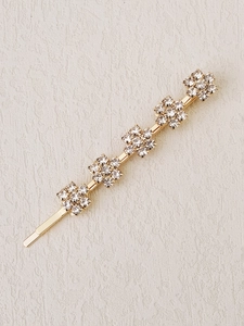 Close-up of golden metal hair clip featuring five shimmering rhinestone flower charms