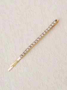 Macro shot of gold metal hair clip featuring a line of sparkly clear rhinestones
