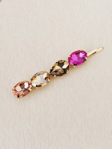 Detailed close-up of crystal hair pins with colorful rhinestones on a gold base